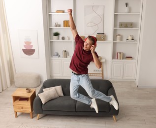 Photo of Happy man jumping while listening to music at home