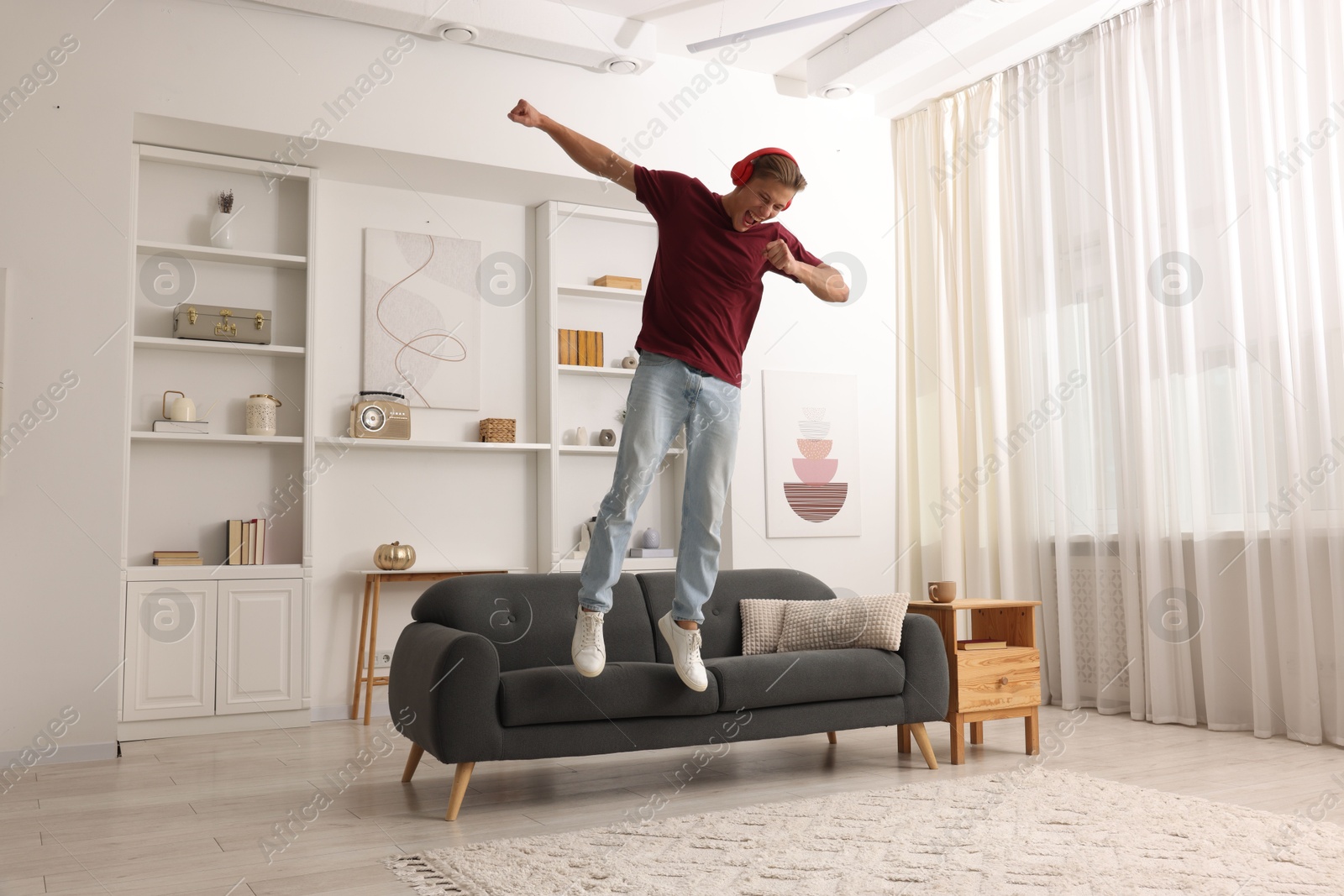 Happy man jumping while listening to music at home Photo of Happy man jumping while listening to music at home
