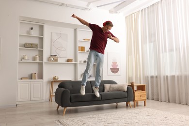 Photo of Happy man jumping while listening to music at home