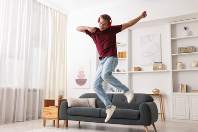 Photo of Happy man jumping while listening to music at home