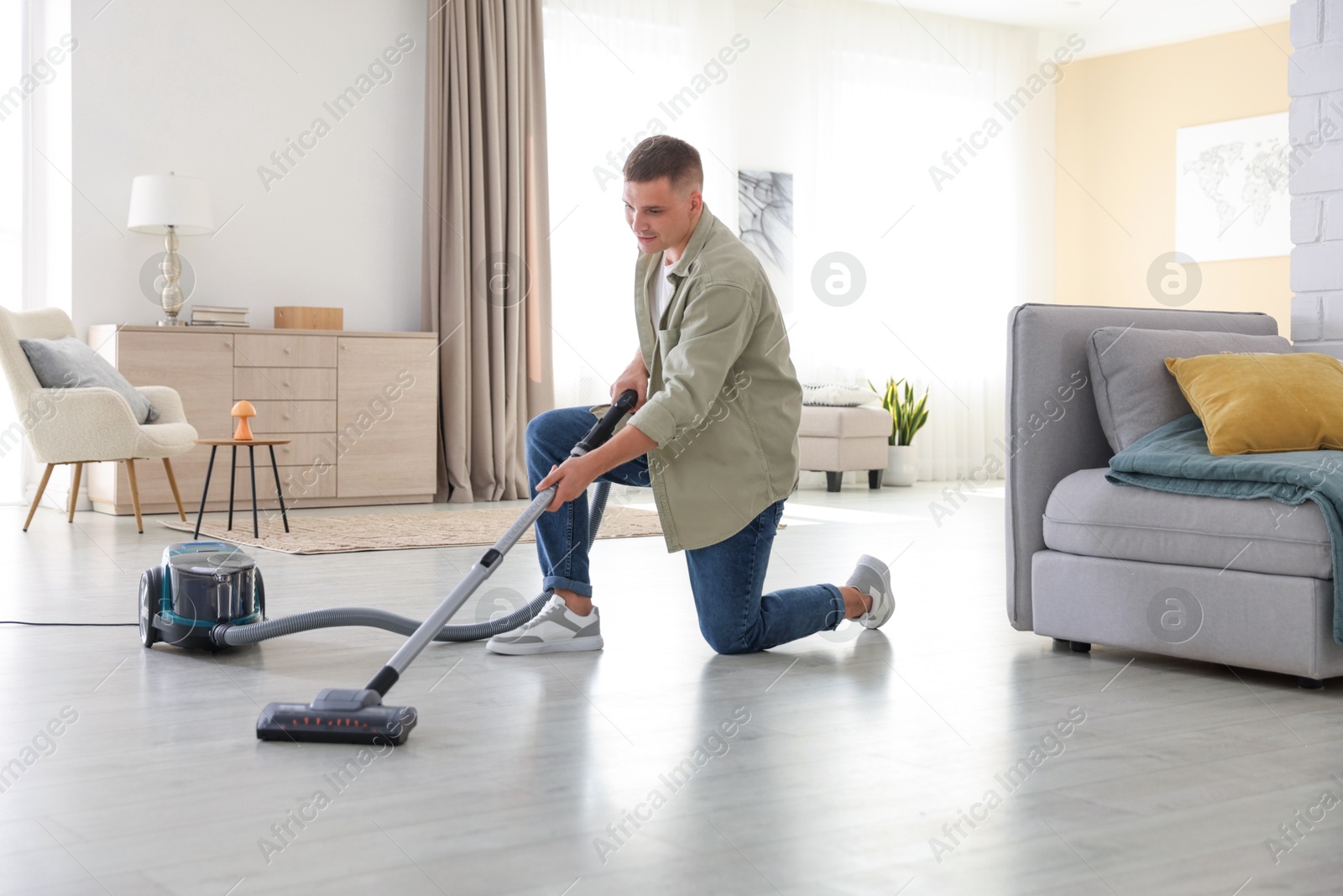 Man cleaning floor with vacuum cleaner at home Photo of Man cleaning floor with vacuum cleaner at home