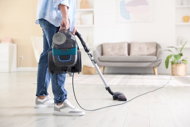 Photo of Man cleaning floor with vacuum cleaner at home, closeup. Space for text