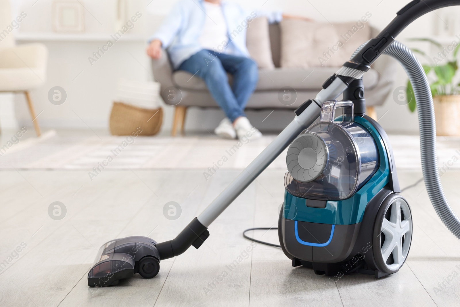 Man resting on sofa at home, focus on vacuum cleaner Photo of Man resting on sofa at home, focus on vacuum cleaner