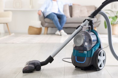 Photo of Man resting on sofa at home, focus on vacuum cleaner