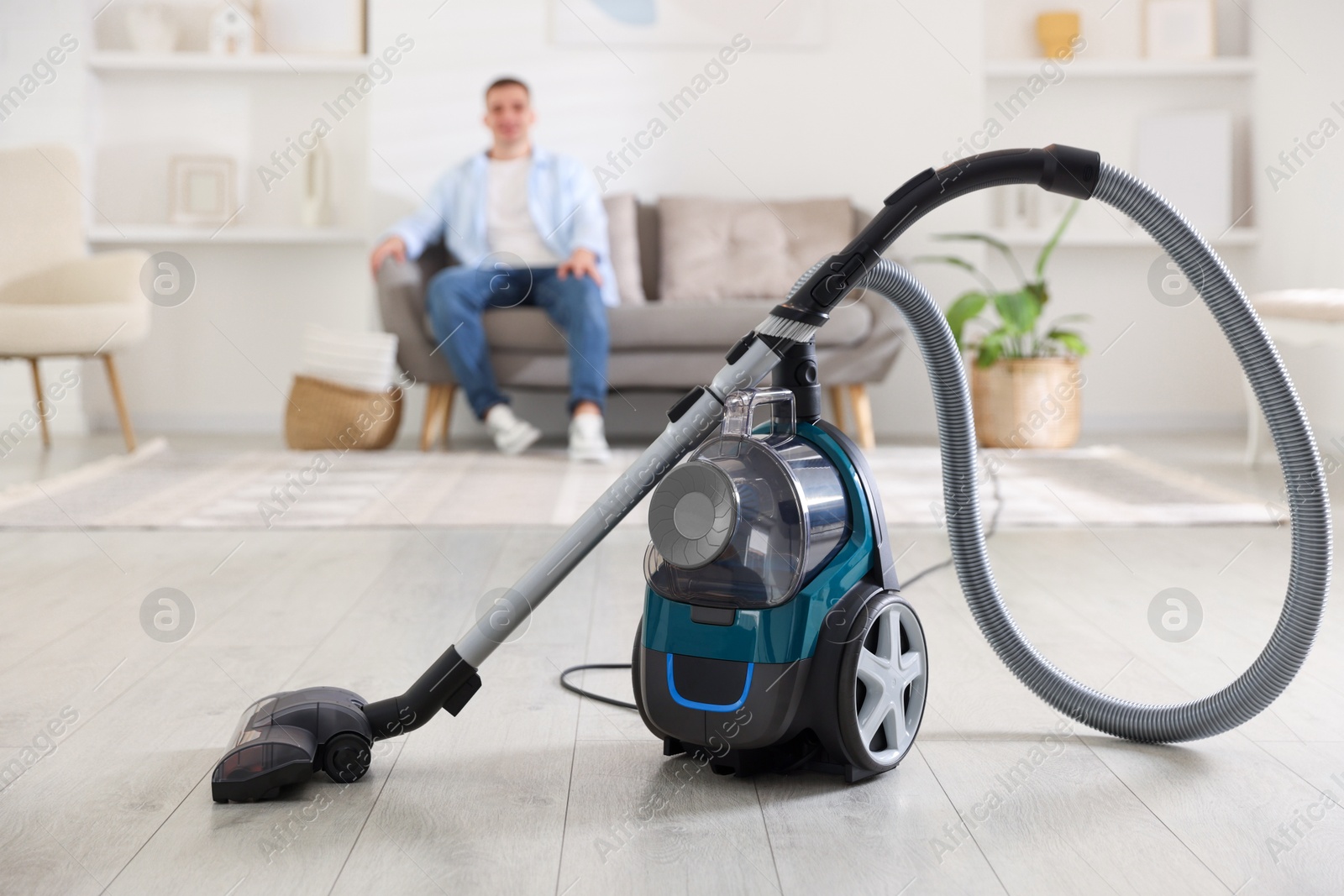 Man resting on sofa at home, focus on vacuum cleaner Photo of Man resting on sofa at home, focus on vacuum cleaner