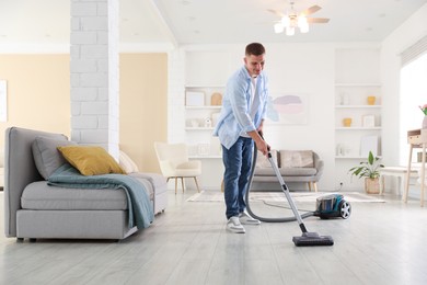 Photo of Man cleaning floor with vacuum cleaner at home