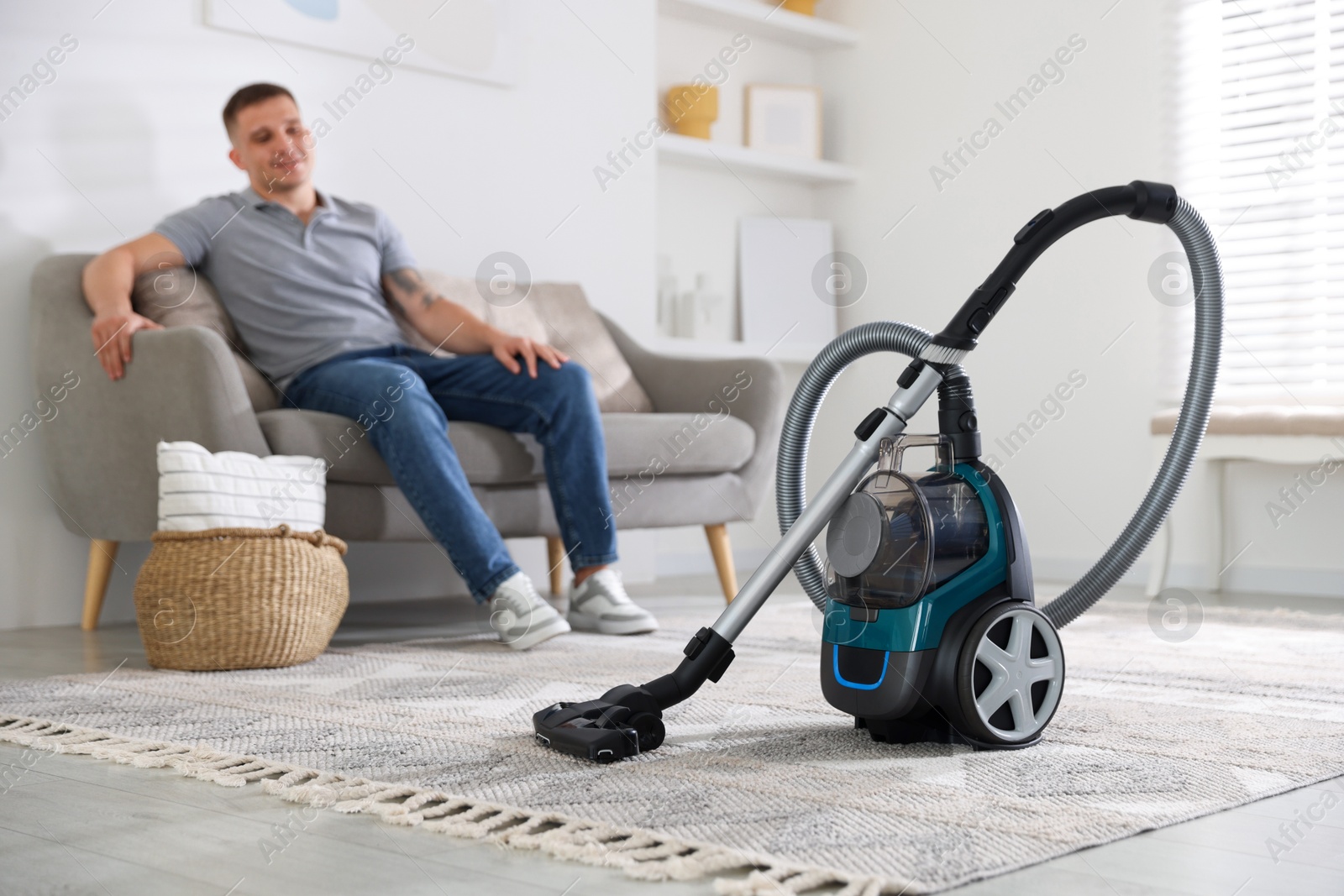 Man resting on sofa at home, focus on vacuum cleaner Photo of Man resting on sofa at home, focus on vacuum cleaner
