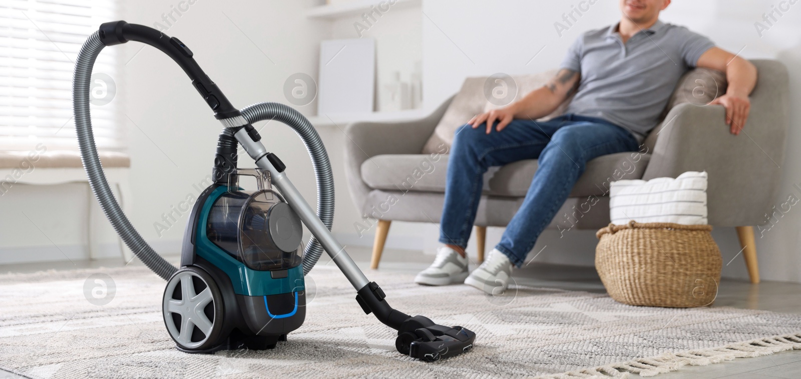 Man resting on sofa at home, focus on vacuum cleaner Photo of Man resting on sofa at home, focus on vacuum cleaner