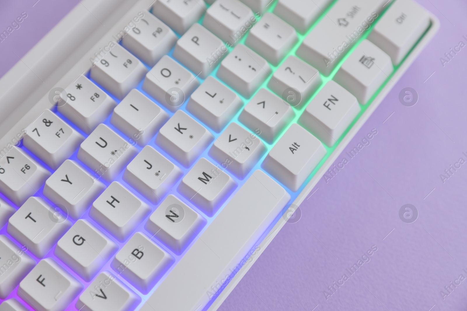 Modern computer keyboard with RGB lighting on violet background, above view Photo of Modern computer keyboard with RGB lighting on violet background, above view