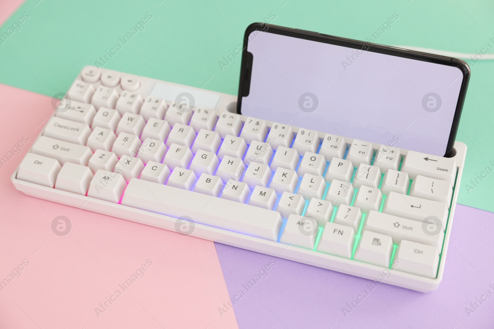 Modern computer keyboard with RGB lighting and smartphone on color background, closeup Photo of Modern computer keyboard with RGB lighting and smartphone on color background, closeup