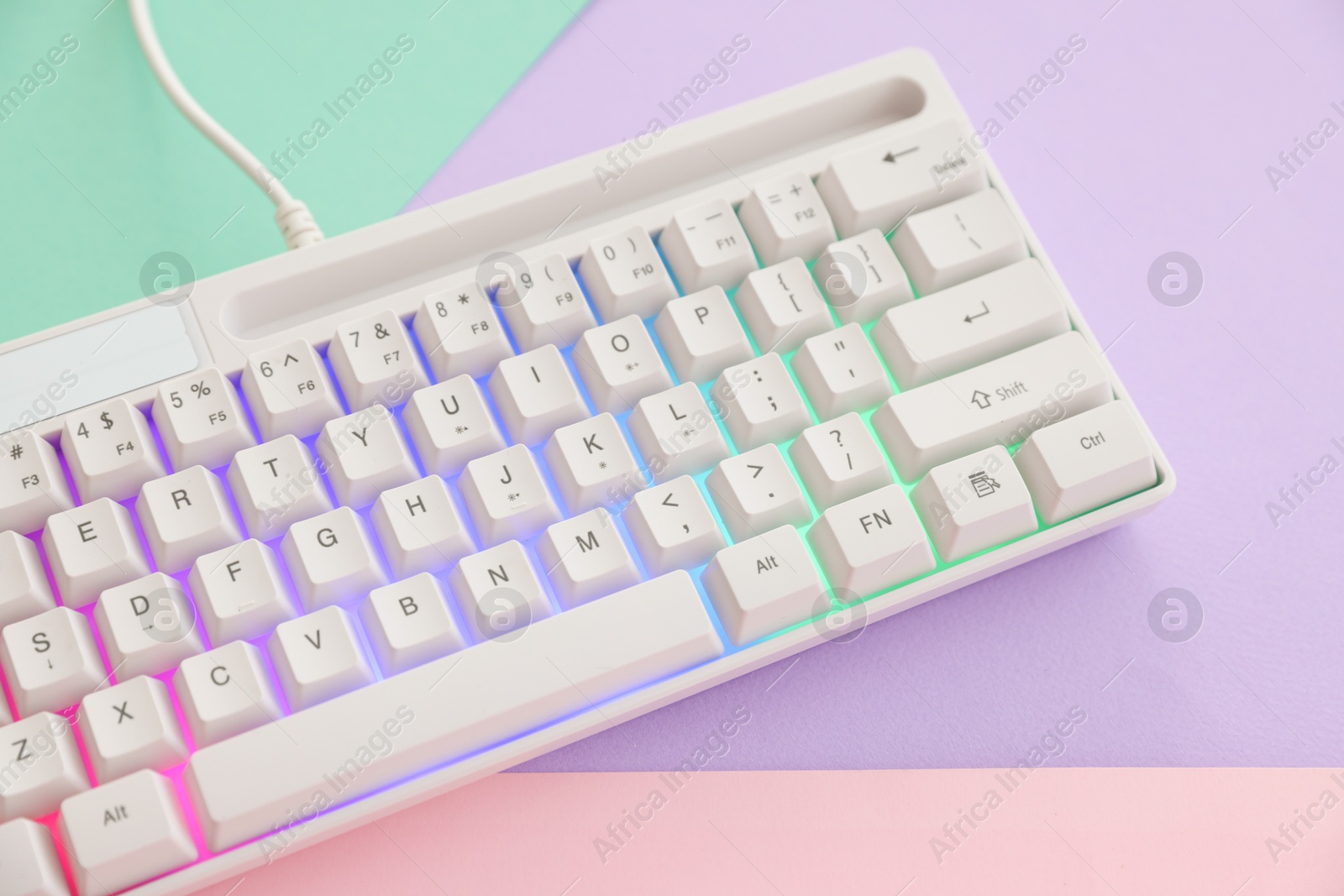 Modern computer keyboard with RGB lighting on color background, above view Photo of Modern computer keyboard with RGB lighting on color background, above view