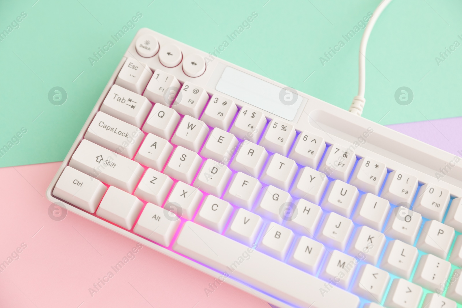 Modern computer keyboard with RGB lighting on color background, above view Photo of Modern computer keyboard with RGB lighting on color background, above view