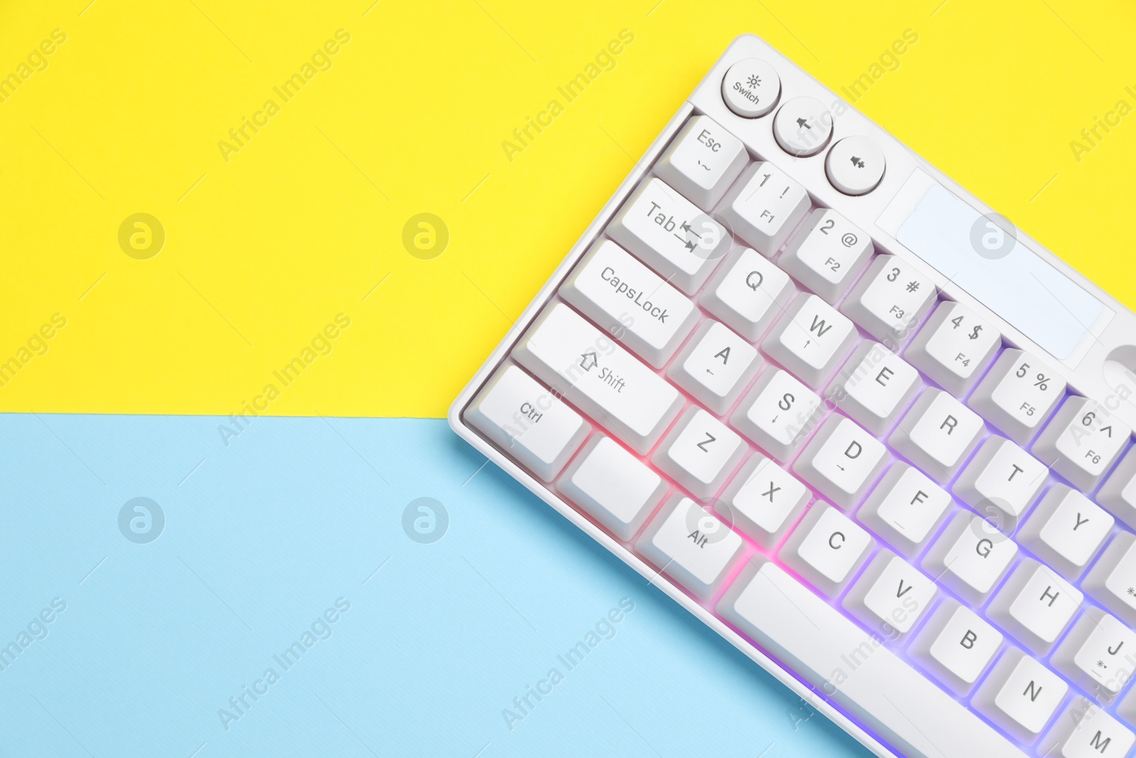 Photo of Modern white keyboard with RGB lighting on color background, top view. Space for text