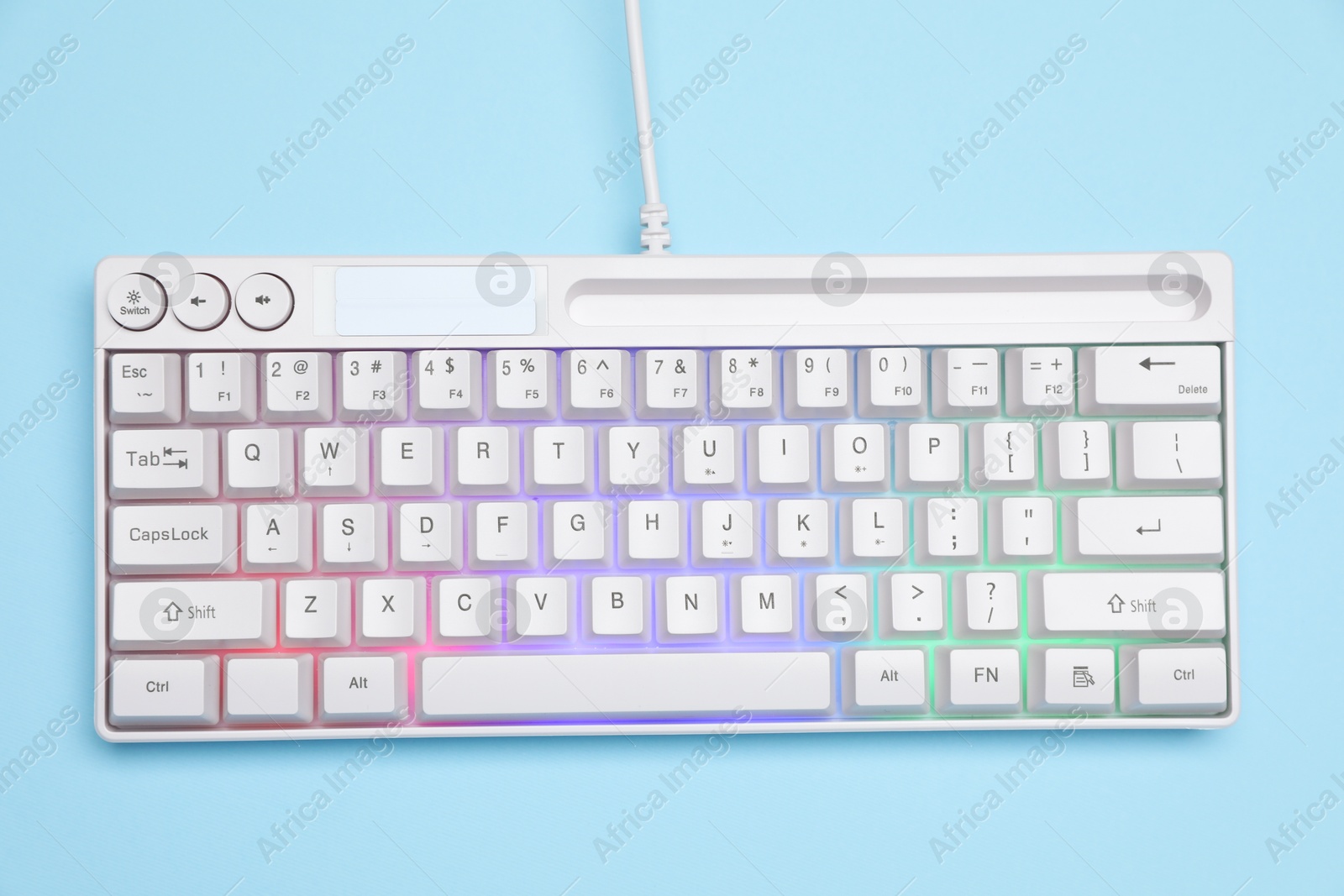 Photo of Modern white keyboard with RGB lighting on light blue background