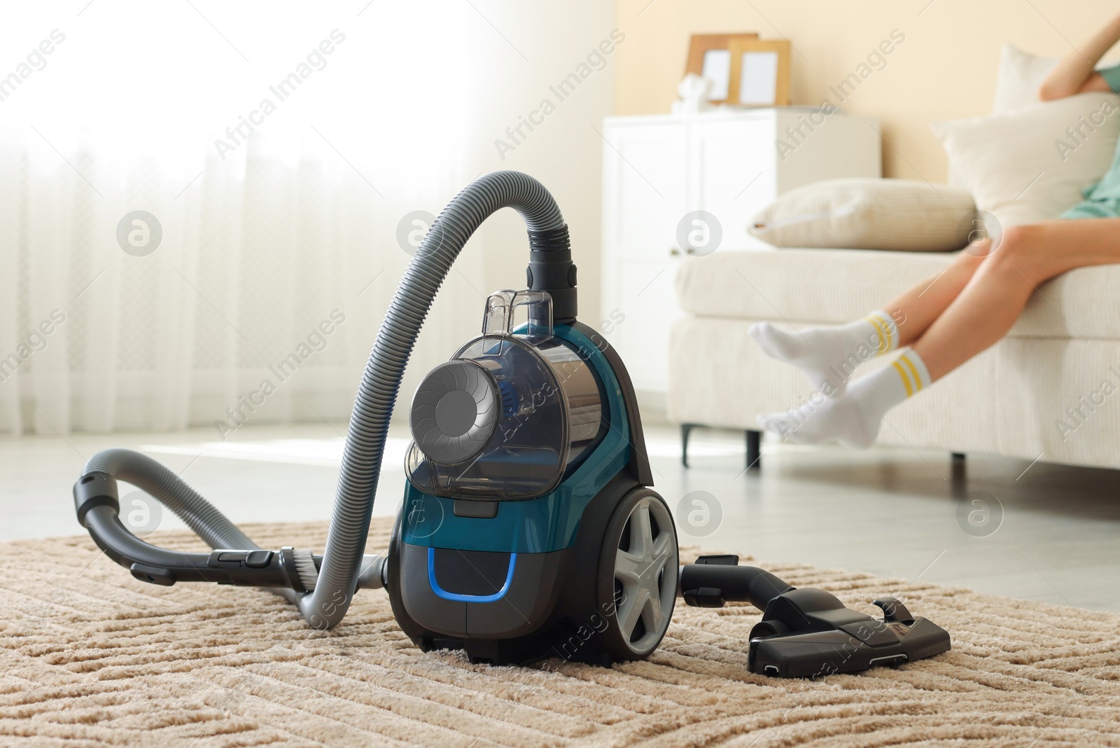 Woman resting on sofa at home, focus on vacuum cleaner Photo of Woman resting on sofa at home, focus on vacuum cleaner