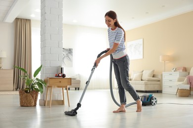 Photo of Woman cleaning floor with vacuum cleaner at home