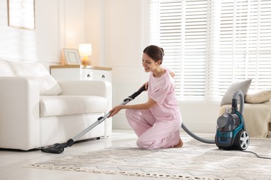 Photo of Woman cleaning floor with vacuum cleaner at home