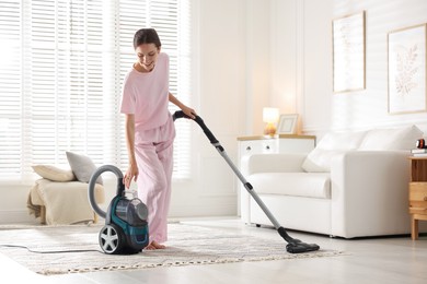 Photo of Woman cleaning carpet with vacuum cleaner at home