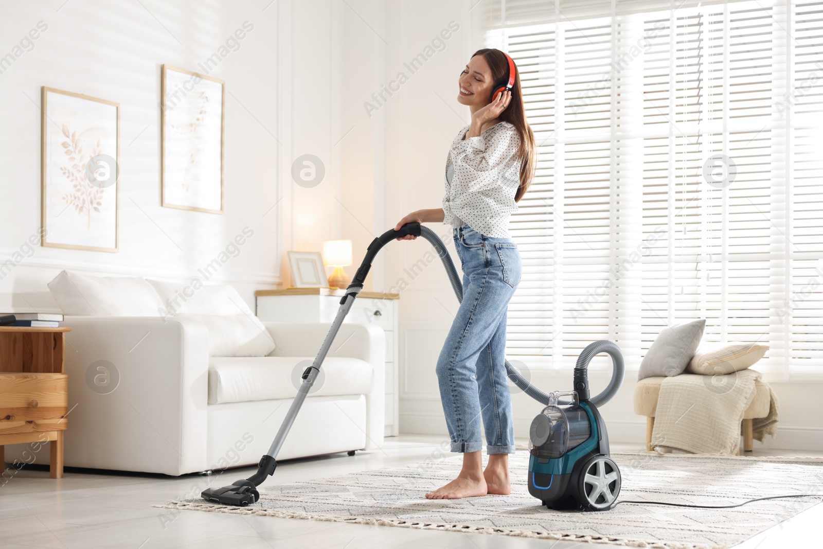 Woman in headphones cleaning carpet with vacuum cleaner at home Photo of Woman in headphones cleaning carpet with vacuum cleaner at home