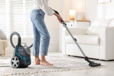 Photo of Woman cleaning carpet with vacuum cleaner at home, closeup