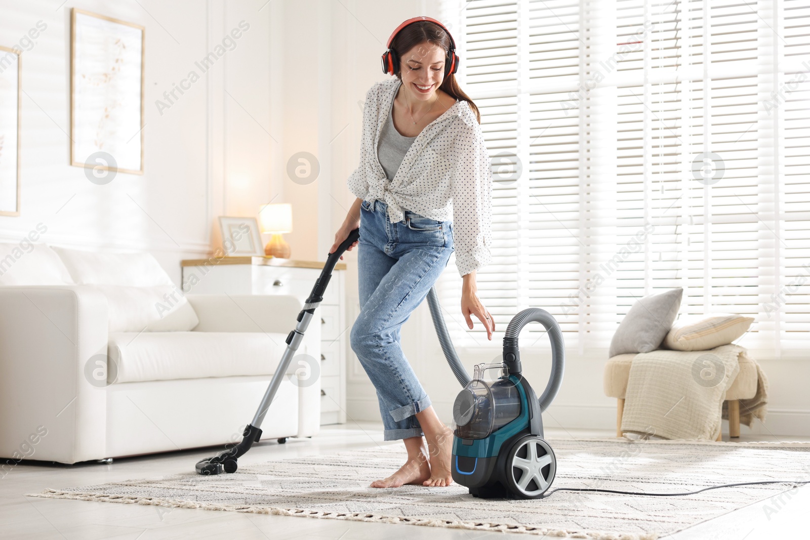 Woman in headphones cleaning carpet with vacuum cleaner at home Photo of Woman in headphones cleaning carpet with vacuum cleaner at home
