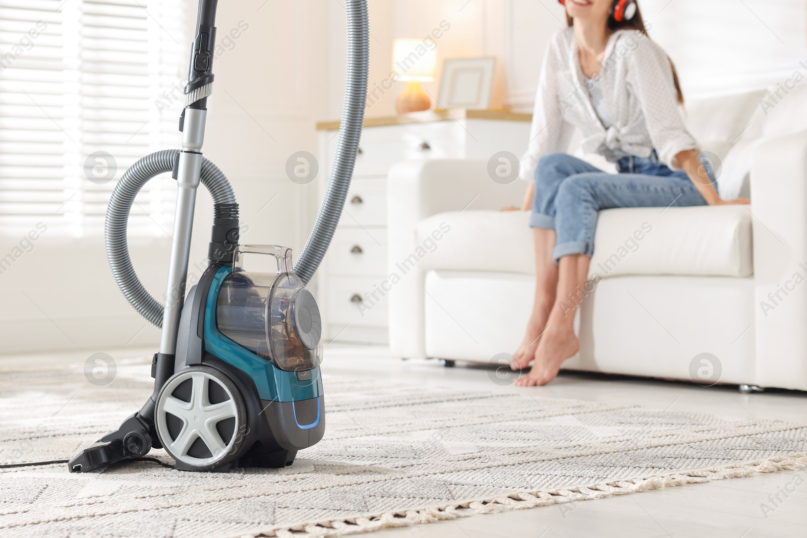 Woman resting on sofa at home, focus on vacuum cleaner Photo of Woman resting on sofa at home, focus on vacuum cleaner