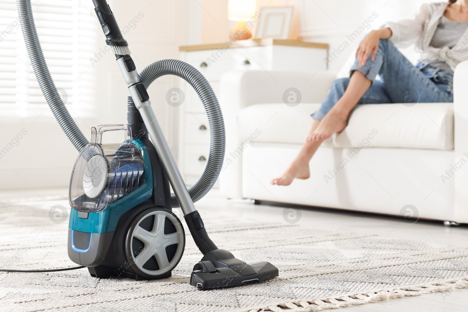 Woman resting on sofa at home, focus on vacuum cleaner Photo of Woman resting on sofa at home, focus on vacuum cleaner
