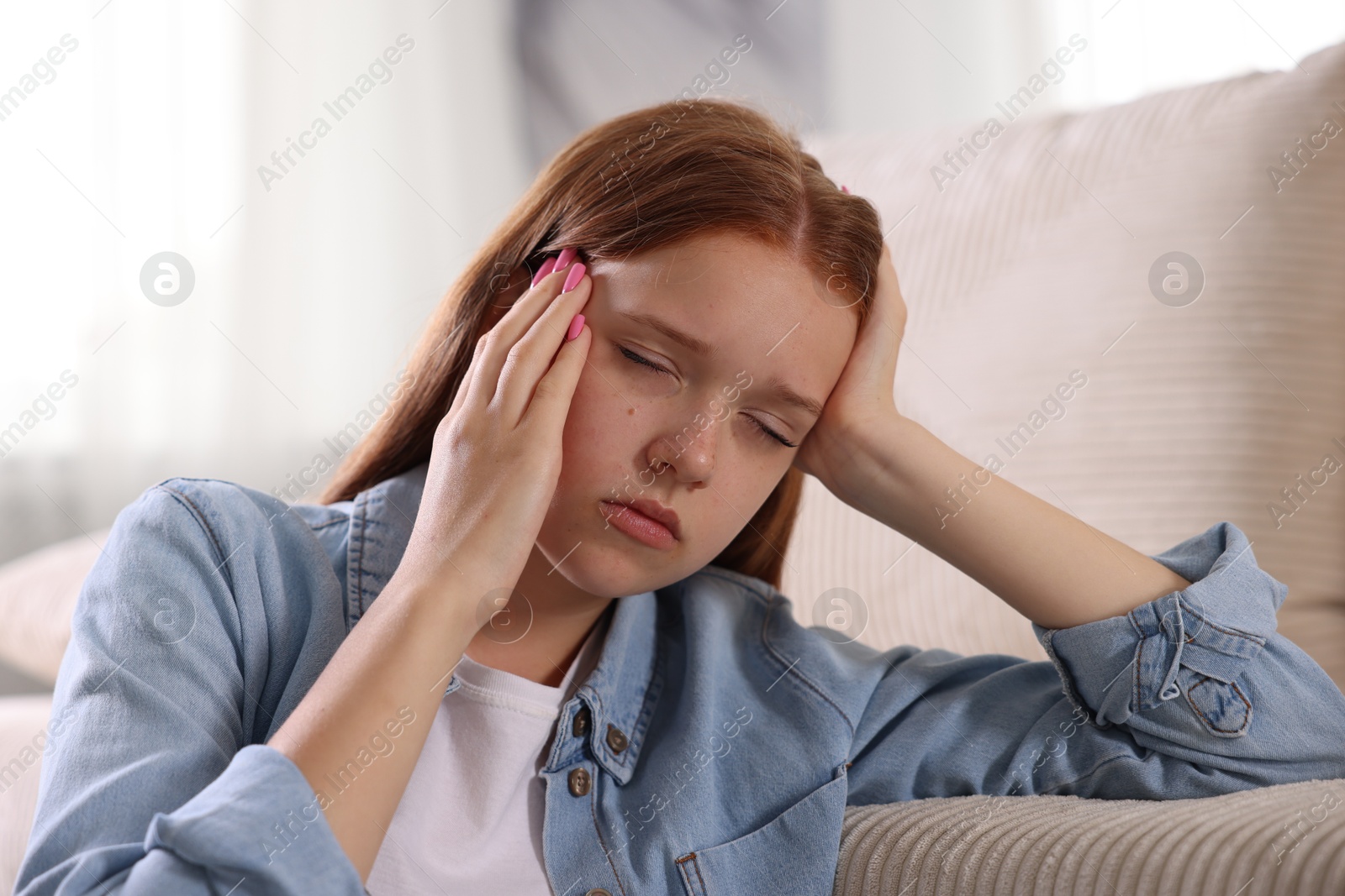 Teenage girl suffering from panic attack leaning on sofa at home Photo of Teenage girl suffering from panic attack leaning on sofa at home