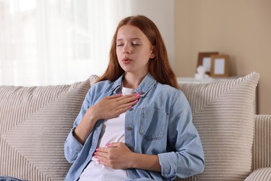Photo of Teenage girl deep breathing on sofa at home. Way to stop panic attack
