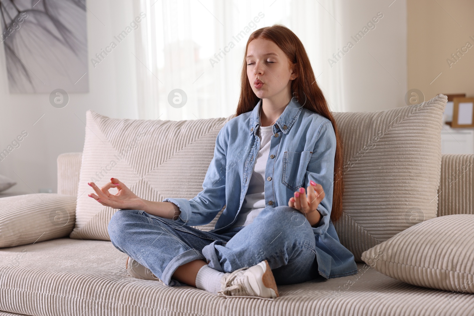 Teenage girl meditating on sofa at home. Way to stop panic attack Photo of Teenage girl meditating on sofa at home. Way to stop panic attack