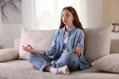 Photo of Teenage girl meditating on sofa at home. Way to stop panic attack
