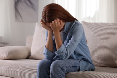 Photo of Teenage girl suffering from panic attack on sofa at home