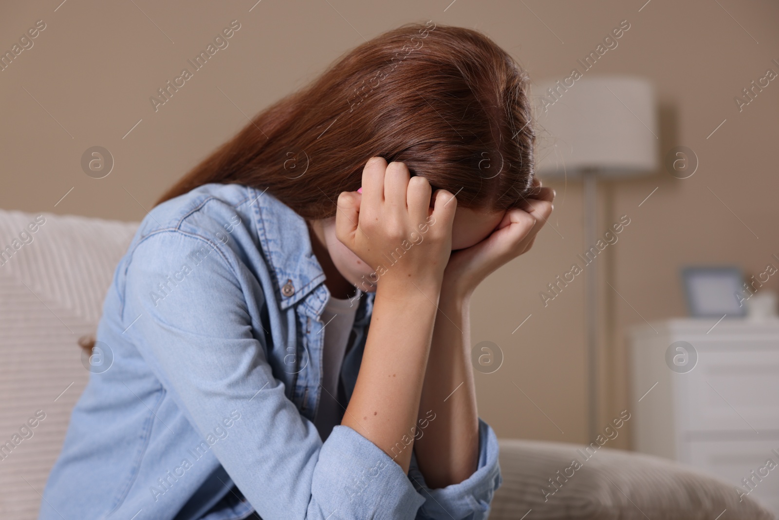 Teenage girl suffering from panic attack on sofa at home Photo of Teenage girl suffering from panic attack on sofa at home
