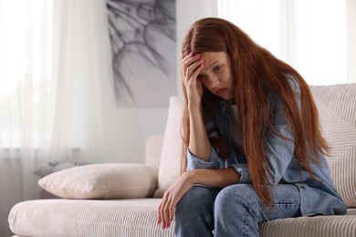Photo of Teenage girl suffering from panic attack on sofa at home. Space for text