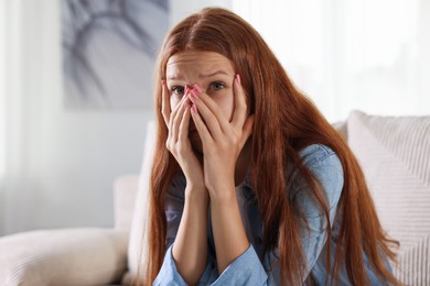 Photo of Teenage girl suffering from panic attack on sofa at home