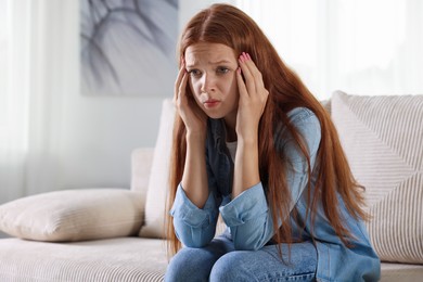 Photo of Teenage girl suffering from panic attack on sofa at home