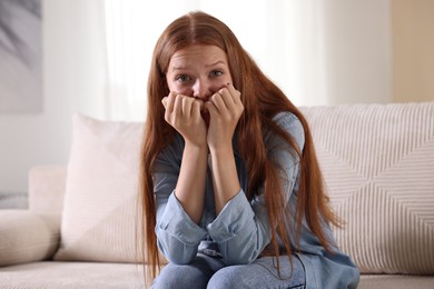 Photo of Teenage girl suffering from panic attack on sofa at home