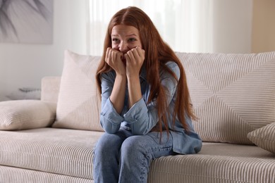 Photo of Teenage girl suffering from panic attack on sofa at home