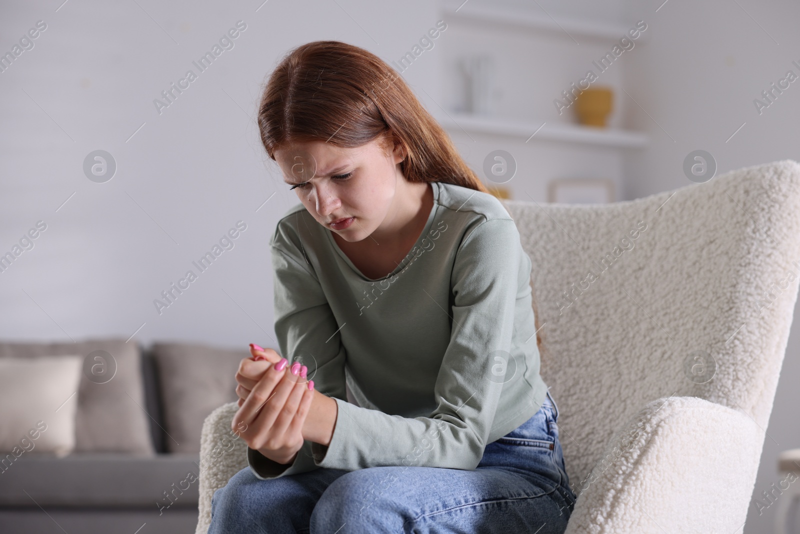 Teenage girl suffering from panic attack on armchair at home Photo of Teenage girl suffering from panic attack on armchair at home