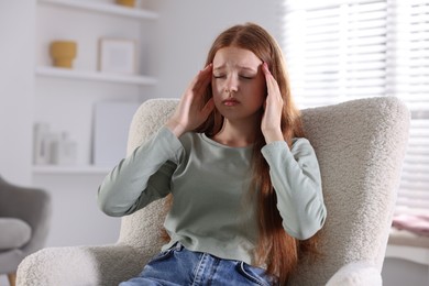 Photo of Teenage girl suffering from panic attack on armchair at home