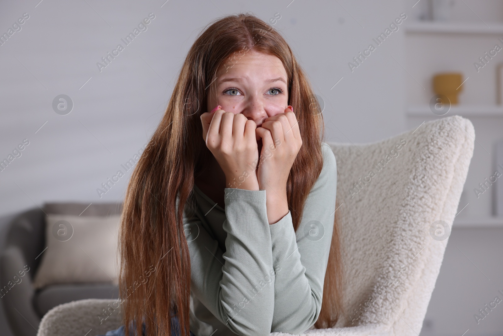 Teenage girl suffering from panic attack on armchair at home Photo of Teenage girl suffering from panic attack on armchair at home