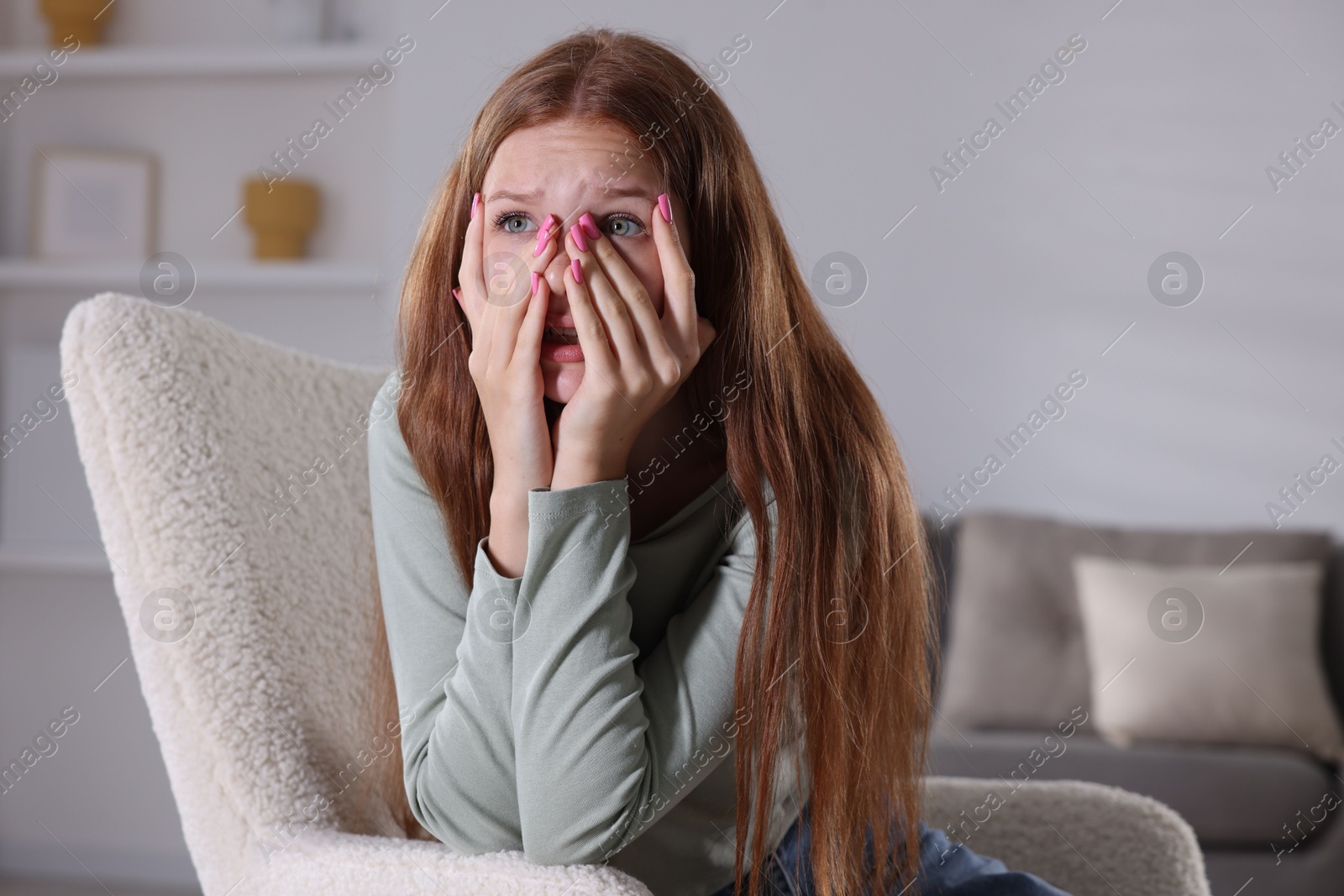 Teenage girl suffering from panic attack on armchair at home Photo of Teenage girl suffering from panic attack on armchair at home