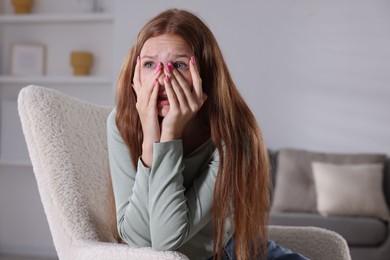 Photo of Teenage girl suffering from panic attack on armchair at home