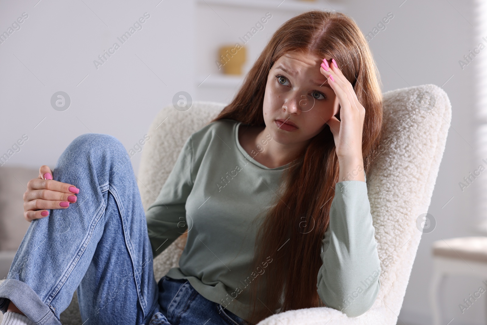 Teenage girl suffering from panic attack on armchair at home Photo of Teenage girl suffering from panic attack on armchair at home