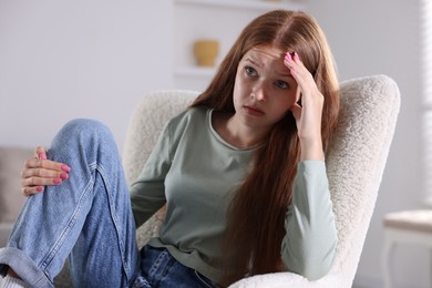 Photo of Teenage girl suffering from panic attack on armchair at home