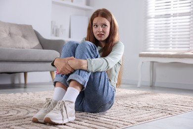 Photo of Teenage girl suffering from panic attack on floor at home