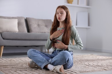 Photo of Teenage girl deep breathing on floor at home. Way to stop panic attack