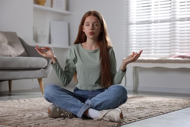 Photo of Teenage girl meditating on floor at home. Way to stop panic attack