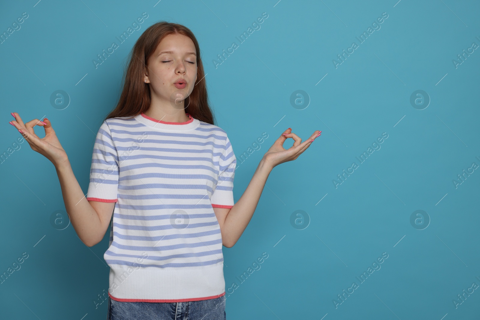 Teenage girl meditating on light blue background, space for text. Way to stop panic attack Photo of Teenage girl meditating on light blue background, space for text. Way to stop panic attack