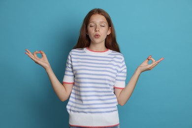 Photo of Teenage girl meditating on light blue background. Way to stop panic attack
